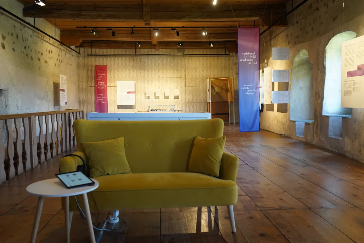 Ein alter Rittersaal mit einem modernen Tisch und Sofa, der als Museumsraum dient.